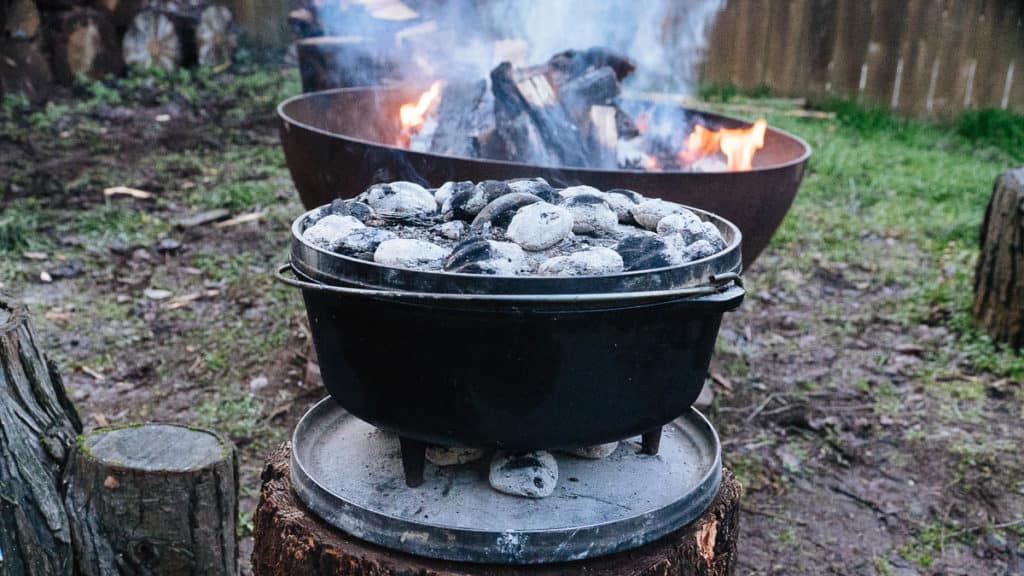 The dutch oven with charcoal briquettes above and below